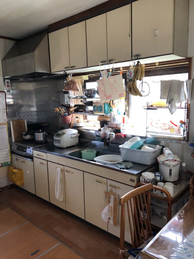 リフォーム前のキッチンです。
開き戸タイプの収納は奥の物が取り出しにくく、カウンター上に調理器具や食器が並んでしまいがちでした。また、勝手口からの隙間風も、冬の寒さの原因となっていました。